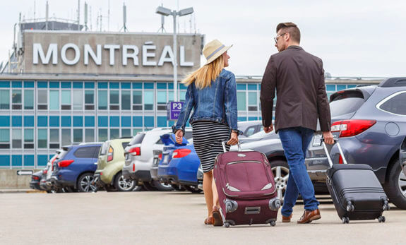two people rolling their luggage throw a parking lot at the montreal airport